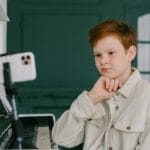 Chłopiec uczy się gry na pianinie online w domowym zaciszu