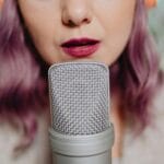 Kobieta o fioletowych włosach mówi do mikrofonu podczas ćwiczeń głosu