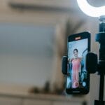 Kobieta prowadząca livestream w domu z telefonem i lampą pierścieniową