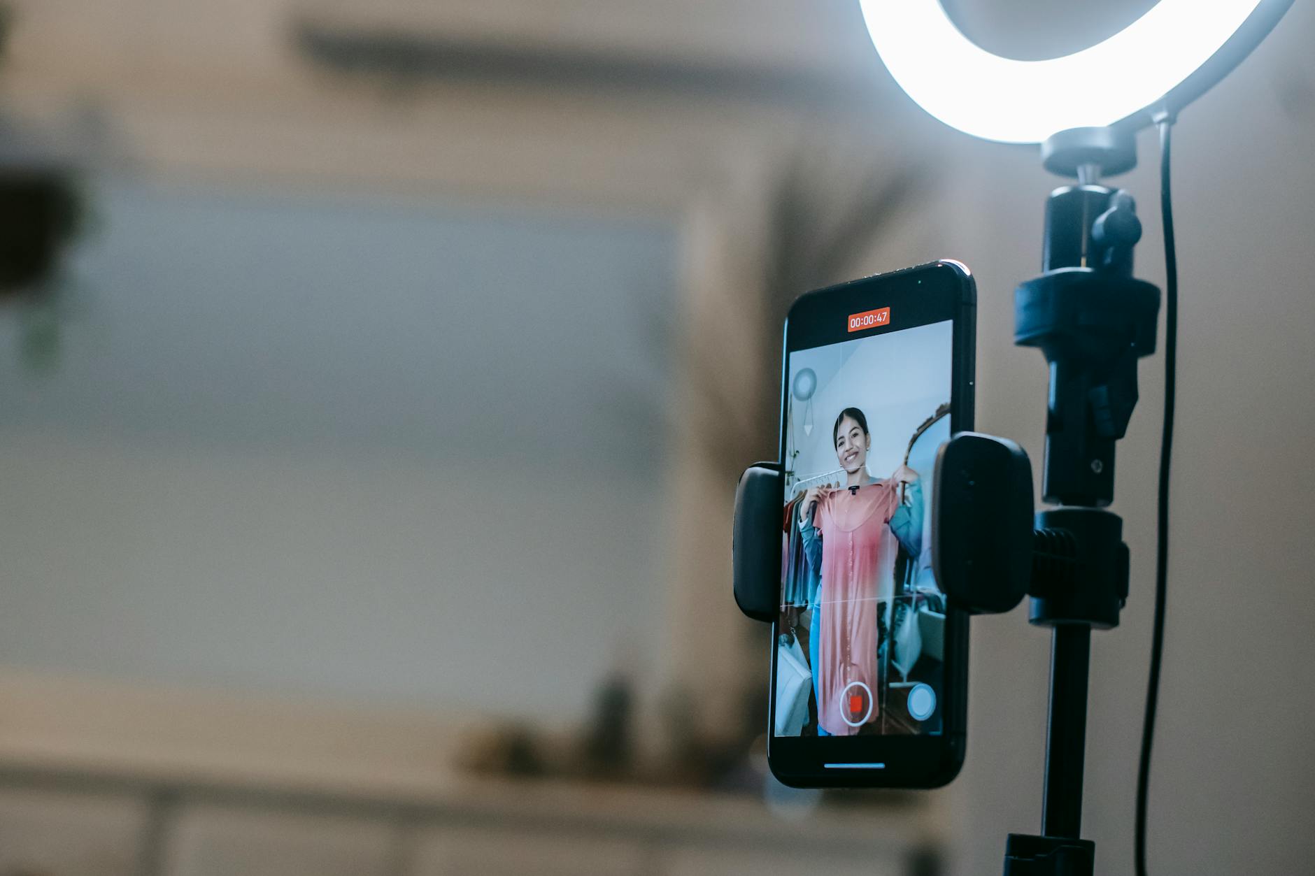 Kobieta prowadząca livestream w domu z telefonem i lampą pierścieniową