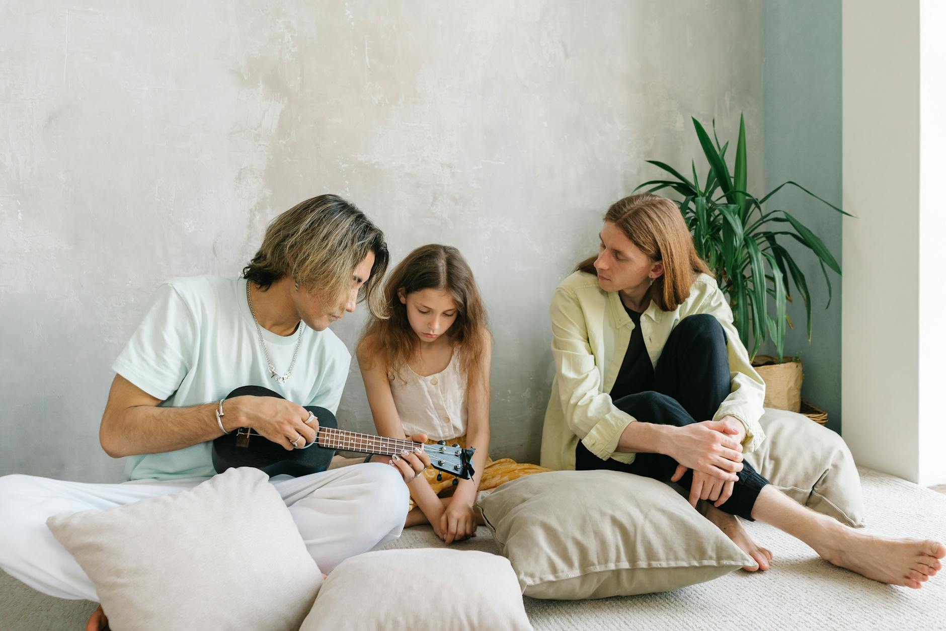 Rodzice i dziecko grają razem na ukulele w domowym salonie