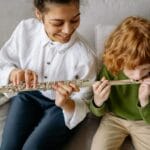 Chłopiec uczy się gry na flecie z nauczycielką w salonie