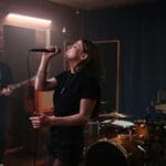 Indie zespół ćwiczy utwór ze słuchu: wokalistka, gitarzysta i perkusista