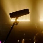 Mikrofon na tle muzyków rockowych na ciemno oświetlonej scenie