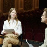 Para młodych aktorów ćwiczy scenę musicalu na jasnej scenie teatru