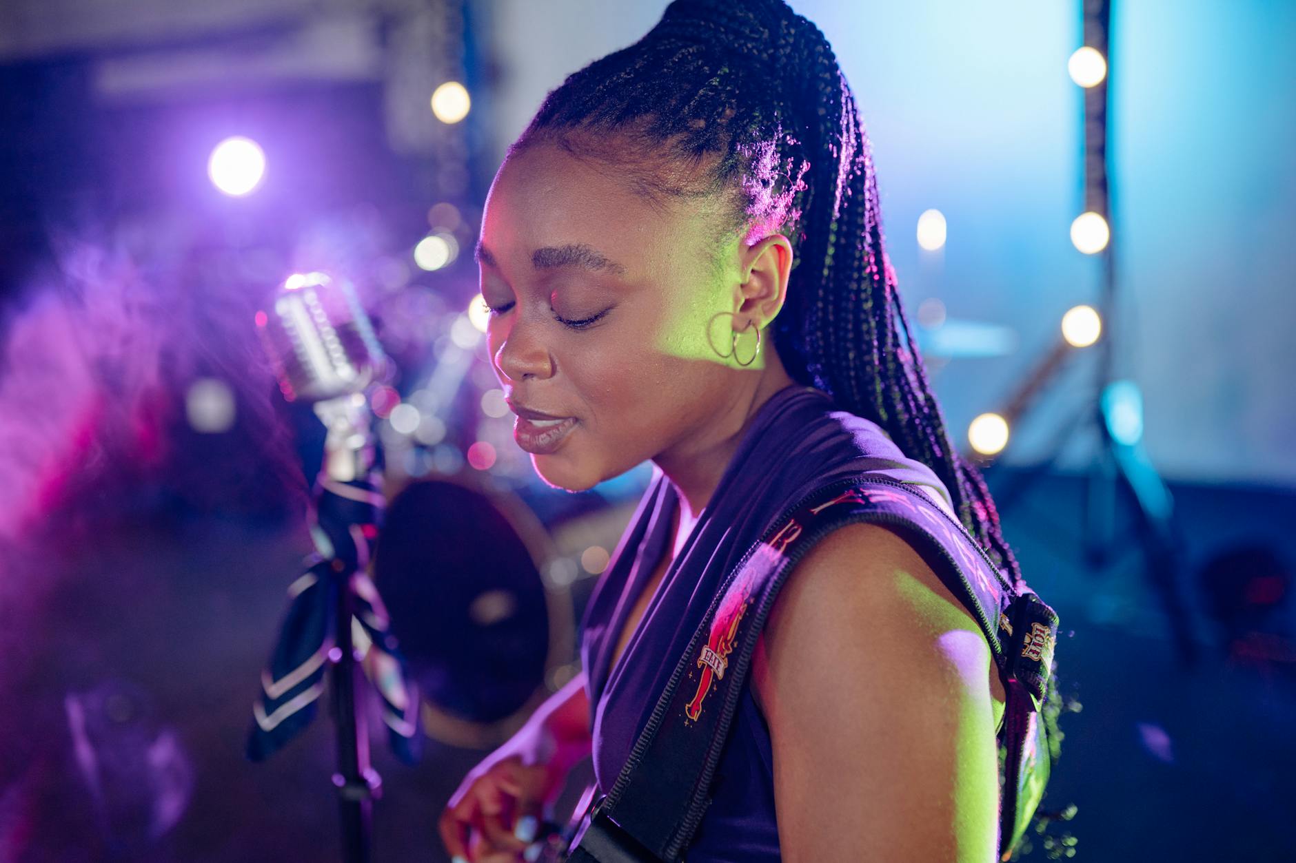 Wokalistka z mikrofonem na kolorowej, oświetlonej scenie