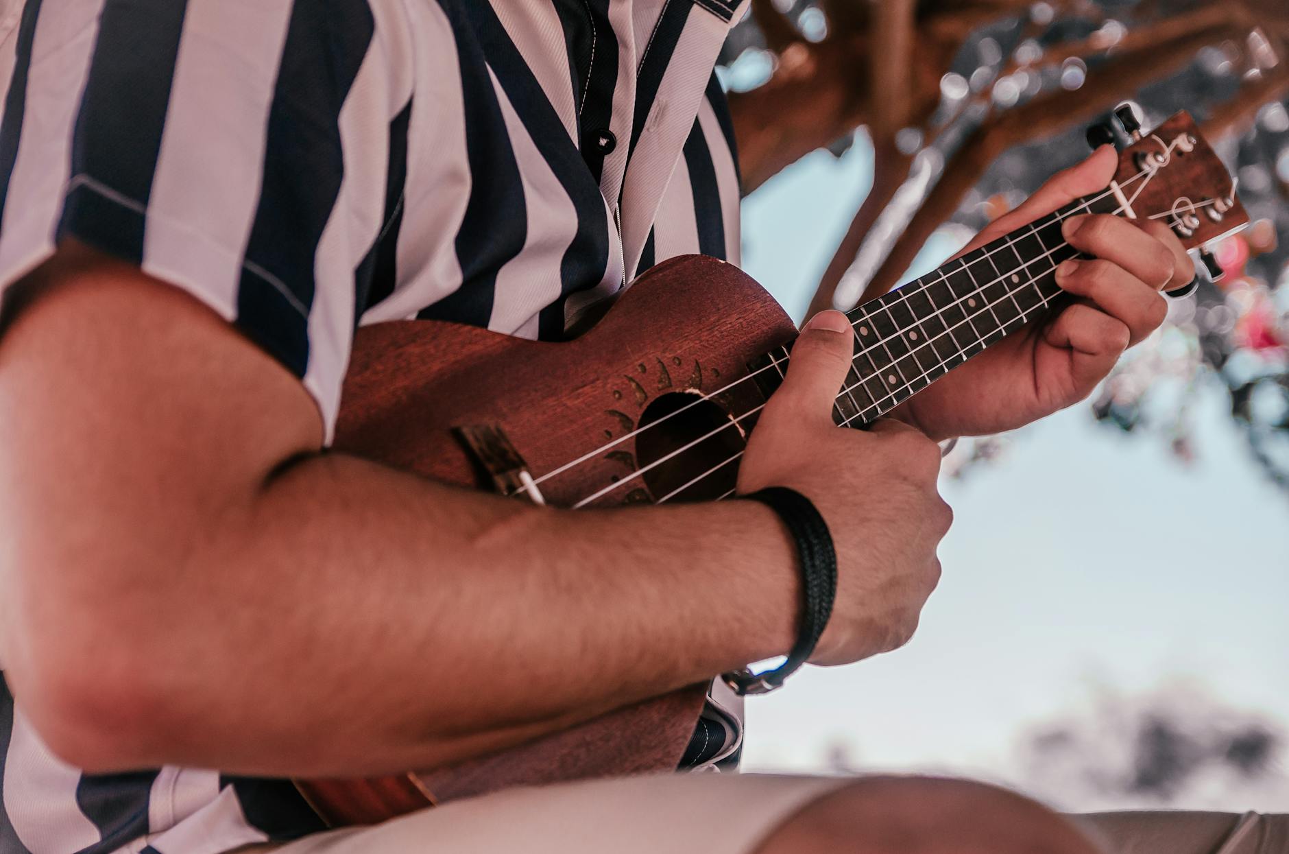 Dłonie szarpiące struny ukulele na świeżym powietrzu