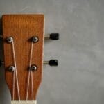 Główka drewnianego ukulele z kluczami stroikowymi na szarym tle