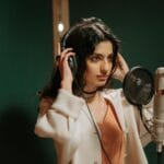 Wokalistka w słuchawkach nagrywa szybki pop w studiu nagraniowym