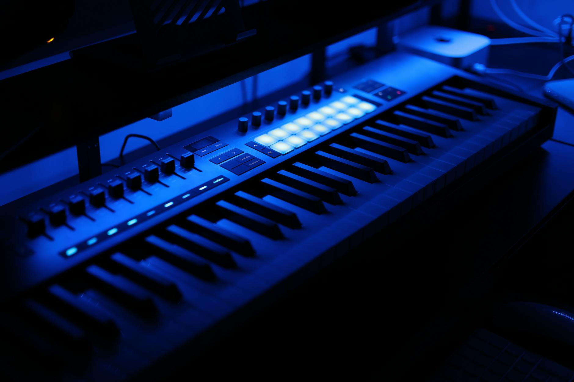Podświetlona na niebiesko klawiatura MIDI w domowym studiu muzycznym