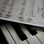Klawiatura fortepianu obok nut z zaznaczonymi łukami frazowania