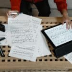 Muzyk analizuje zapis nutowy na tablecie wśród rozłożonych materiałów