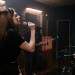 Wokalistka indie ćwiczy staccato z zespołem w studiu muzycznym
