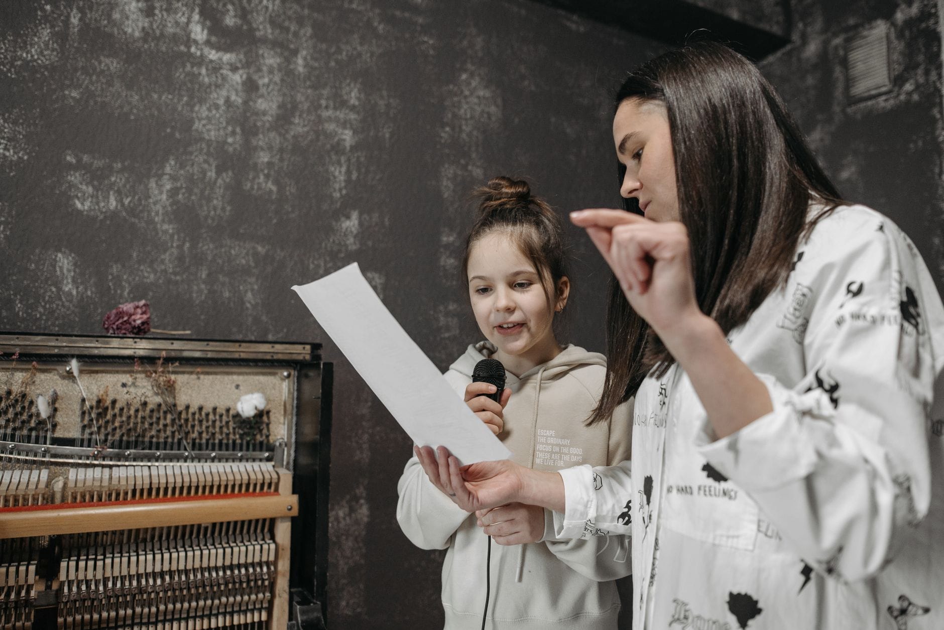 Dziewczynka śpiewa do mikrofonu podczas lekcji w studiu muzycznym